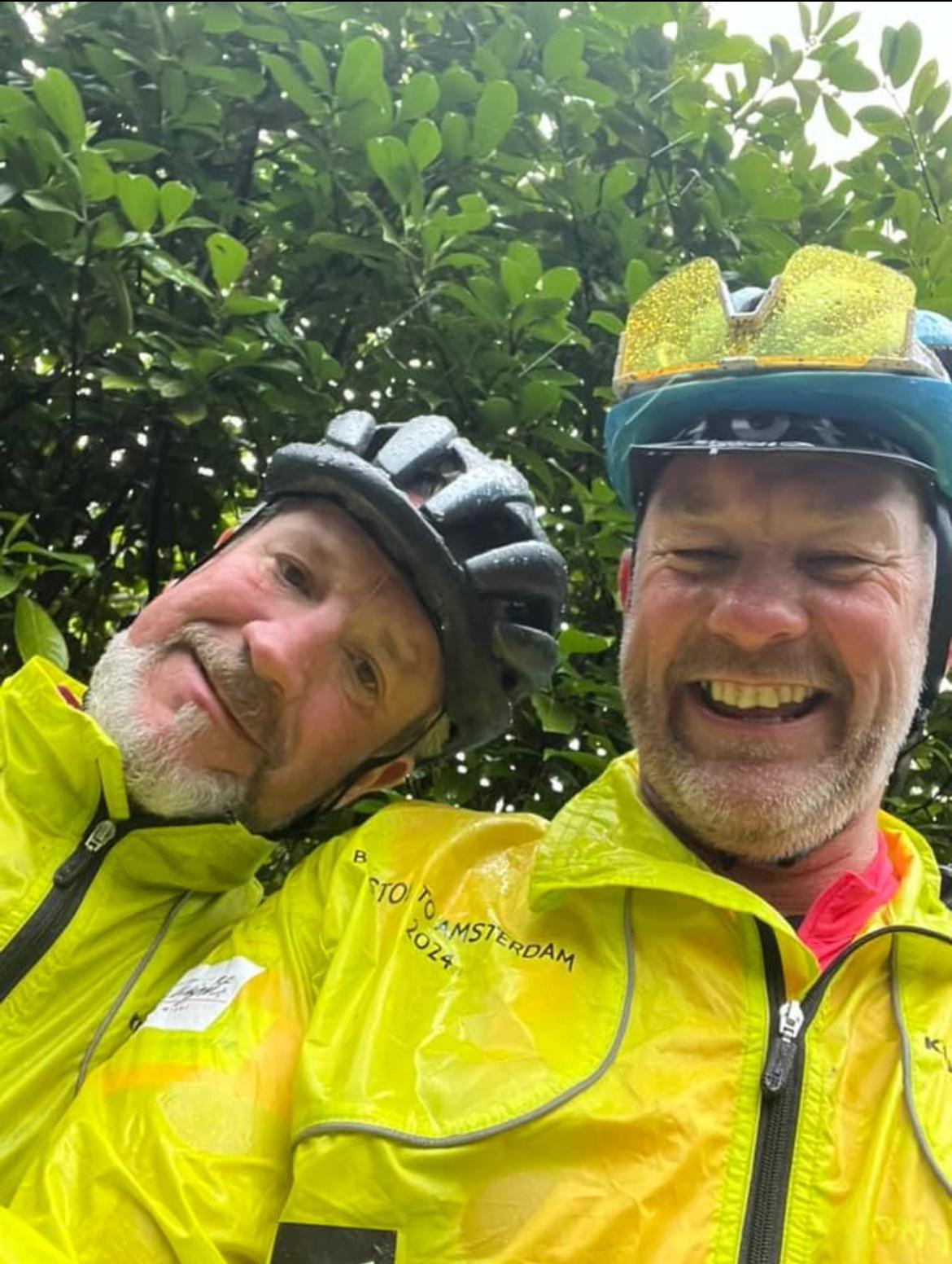Two men wearing helmets and jacketsDescription automatically generated